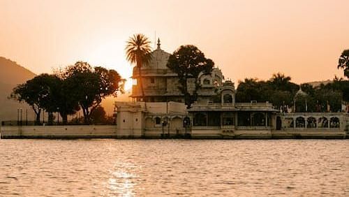 A serene morning view of the majestic Jag Mandir Palace in Udaipur, with its ornate domes and balconies rising from the calm waters of Lake Pichola.