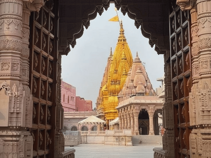 A view through a stone archway leading toward a temple with a gold-plated spire | HHI Varanasi