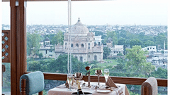 An Awadhi Rooftop Restaurant in Lucknow by a window with a view of a city monument, representing a lavish stay in Lucknow experience at Clarks Avadh, Lucknow.