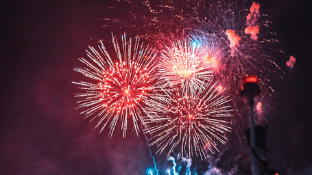 An overview of a lakeside venue with firecrackers in the sky that is illuminated on the waterbody during a New Year Party in Bangkok.