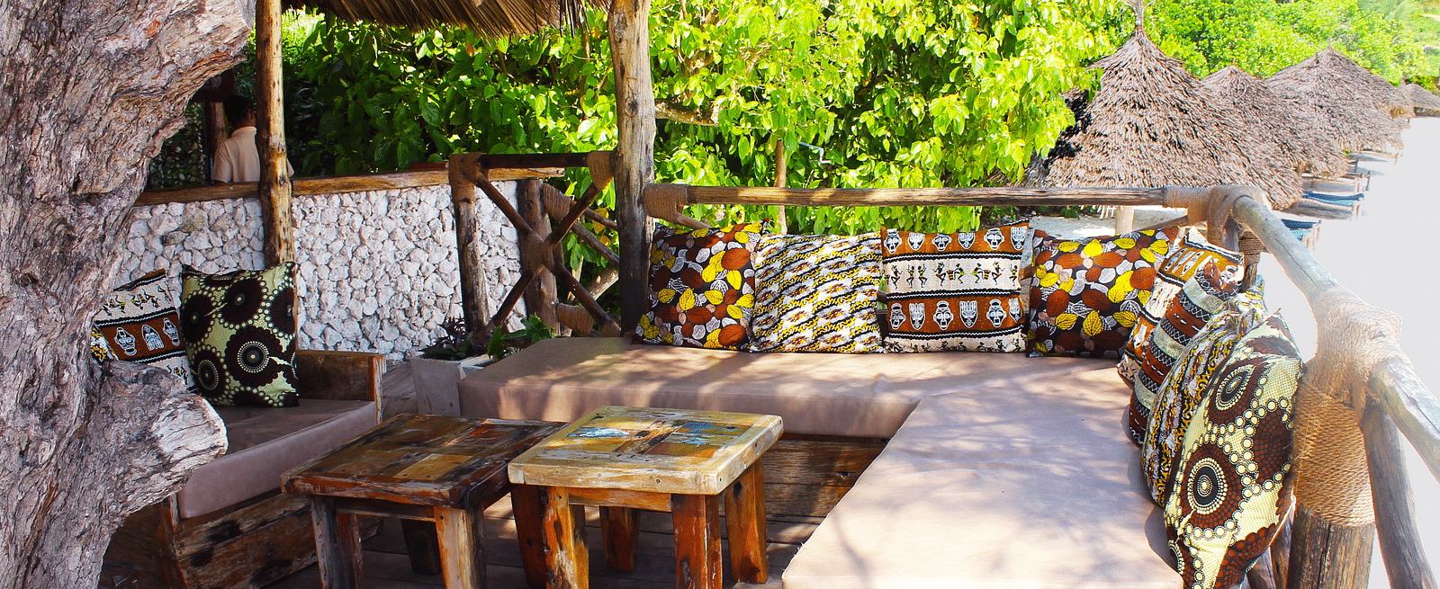 View of Rustic beachside lounge with wooden seating, vibrant cushions, and lush greenery at Shooting Star Boutique Hotel