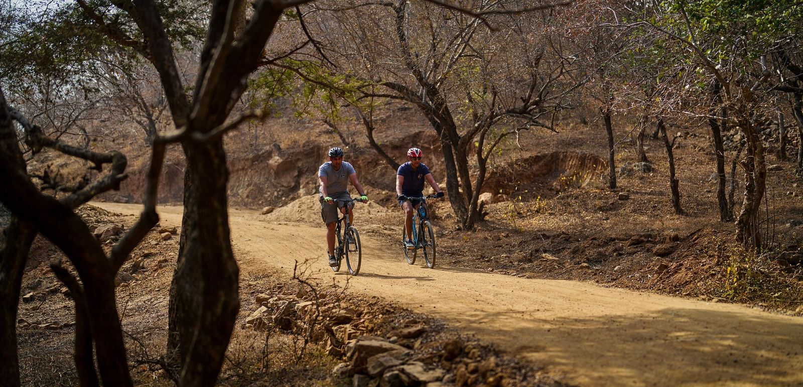 image of two people cycling through the woods through a raw road at dev shree, deogarh