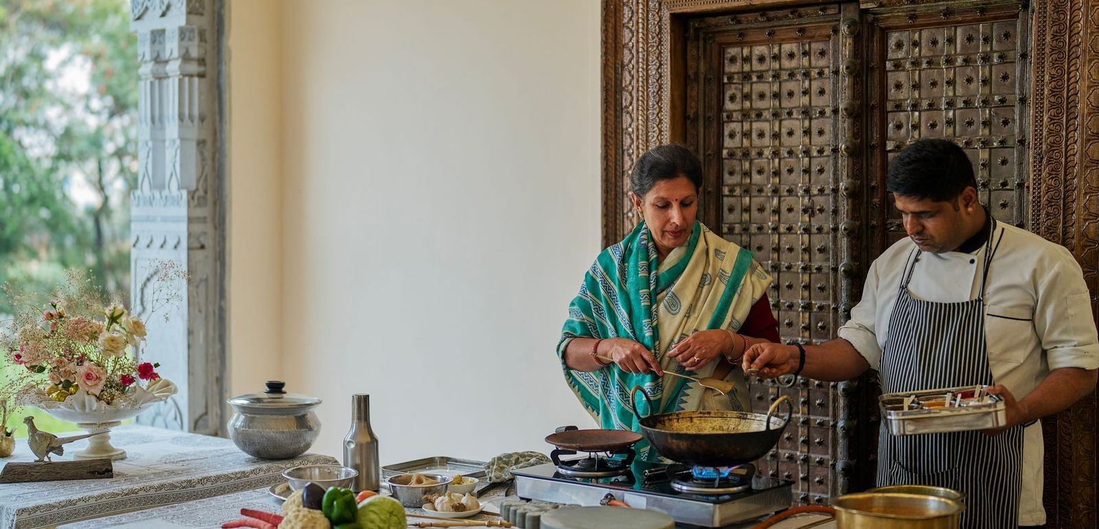 an image of a woman taking culinary classes at Dev Shree, Deogarh along with a trained chef