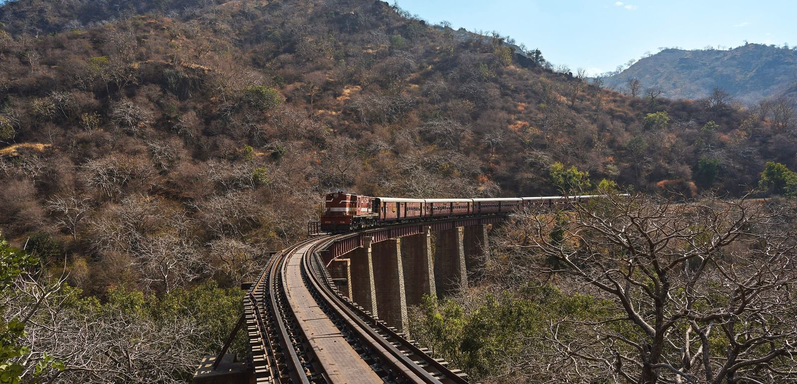 image of a train approaching over a bridge with mountain hills in the background