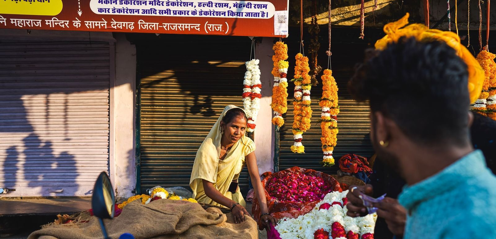 image featuring a woman flower vendor selling various flowers and garlands in a market