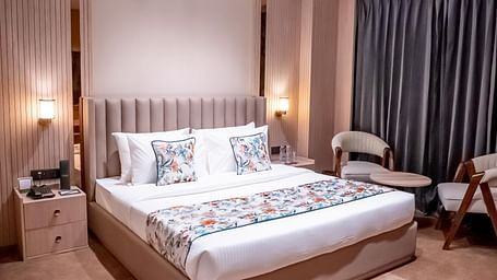 Executive Suite with a bed, bed side tables, chairs and a window with a curtain in the background at ASTER GRAND BY ZENQ SAKET.