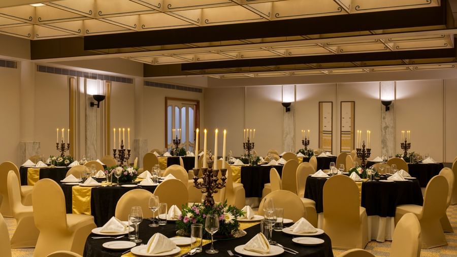  A well-appointed banquet room at Shilton International, Kochi with round tables adorned with settings and candelabras.