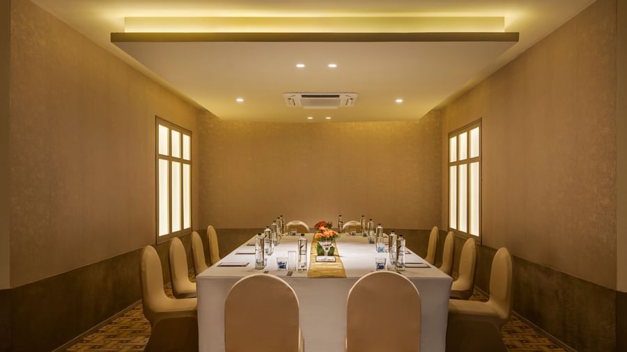  A meeting room at Shilton International, Kochi with a long table surrounded by chairs, set for a formal gathering.