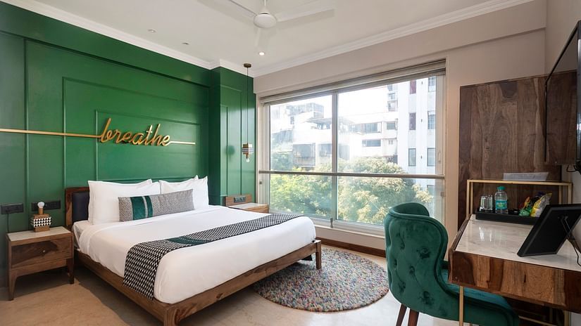 A cozy bedroom featuring a bed, a table with two chairs, and a window offering a view outside