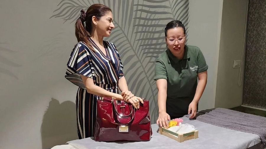 a masseuse explaining things to a customer while inside a massage room - IOSIS Spa & Wellness