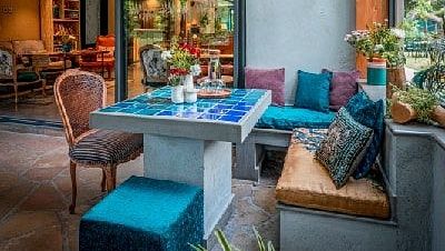 Outdoor seating area at Karma Chalets with cushioned benches, chairs, and plants under a wooden canopy.
