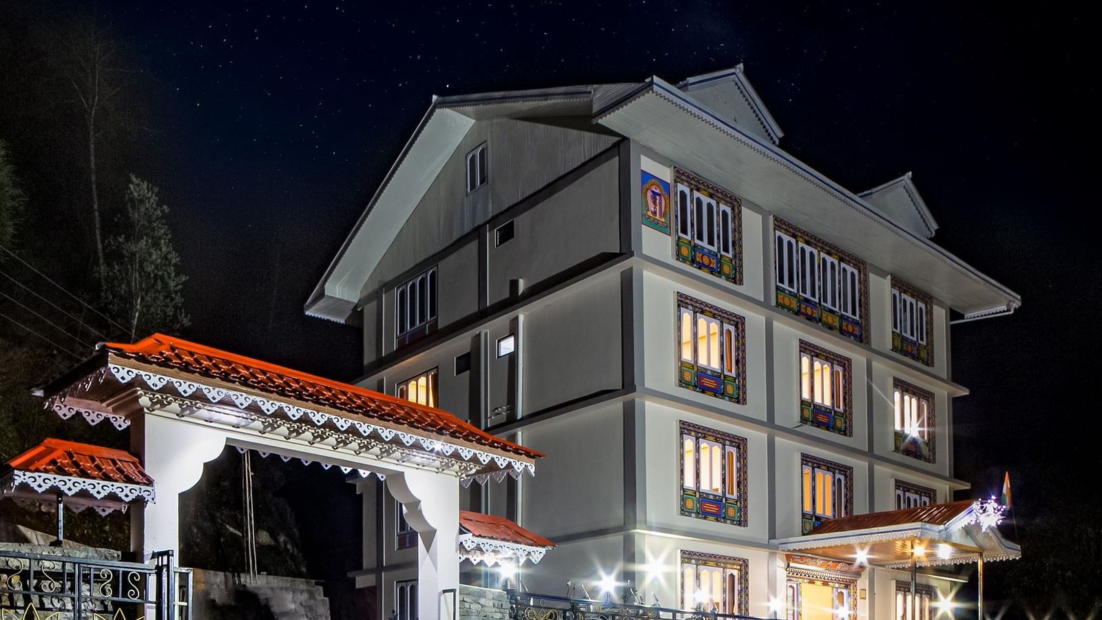 The charming illuminated exterior of Sumitel Sonam Lachung at night, showcasing its traditional architecture.