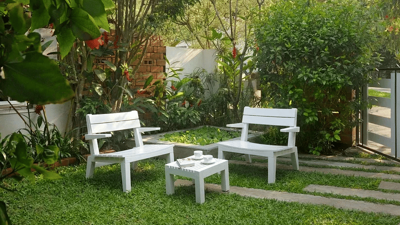 White garden seating set on a green lawn surrounded by trees and plants at Amanvana Spa Resort in Coorg.