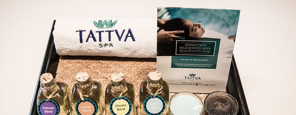 A spa treatment kit is displayed on a tray. It includes a towel with the word TATTVA embroidered on it.