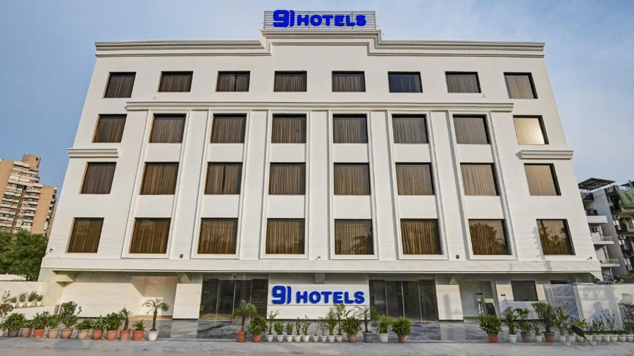 A wide-angle shot of the facade of Hotel 91 Privé, Gurugram, featuring a 4-storey hotel building against a cloudy sky in the background.