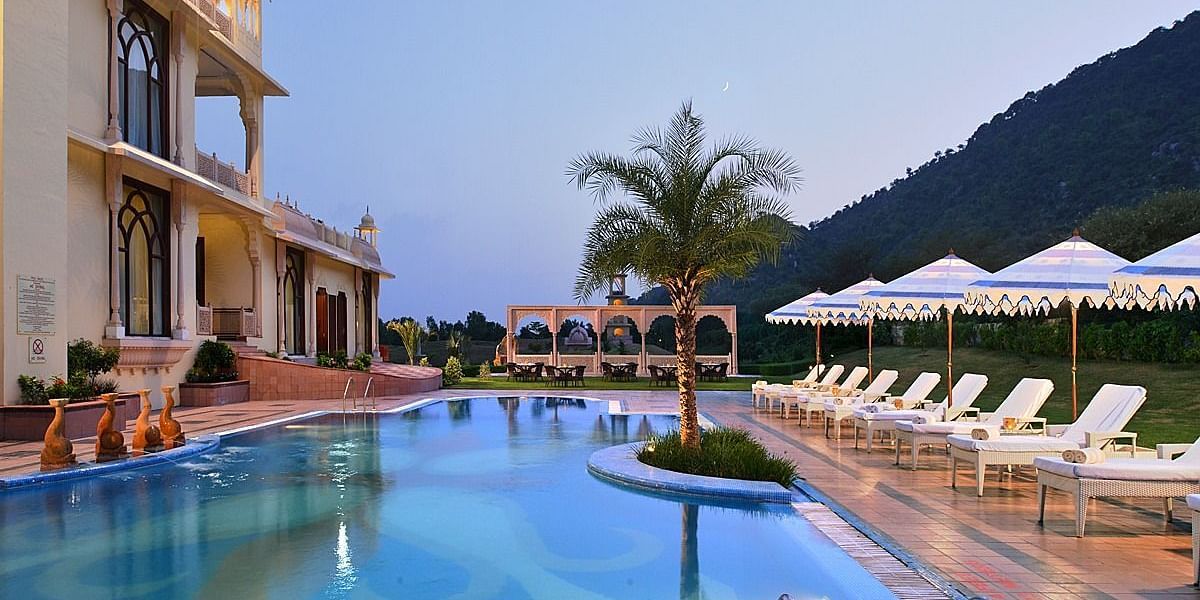 Image of the pool at Rajasthali Resort & Spa Jaipur with lounge chairs on the side.