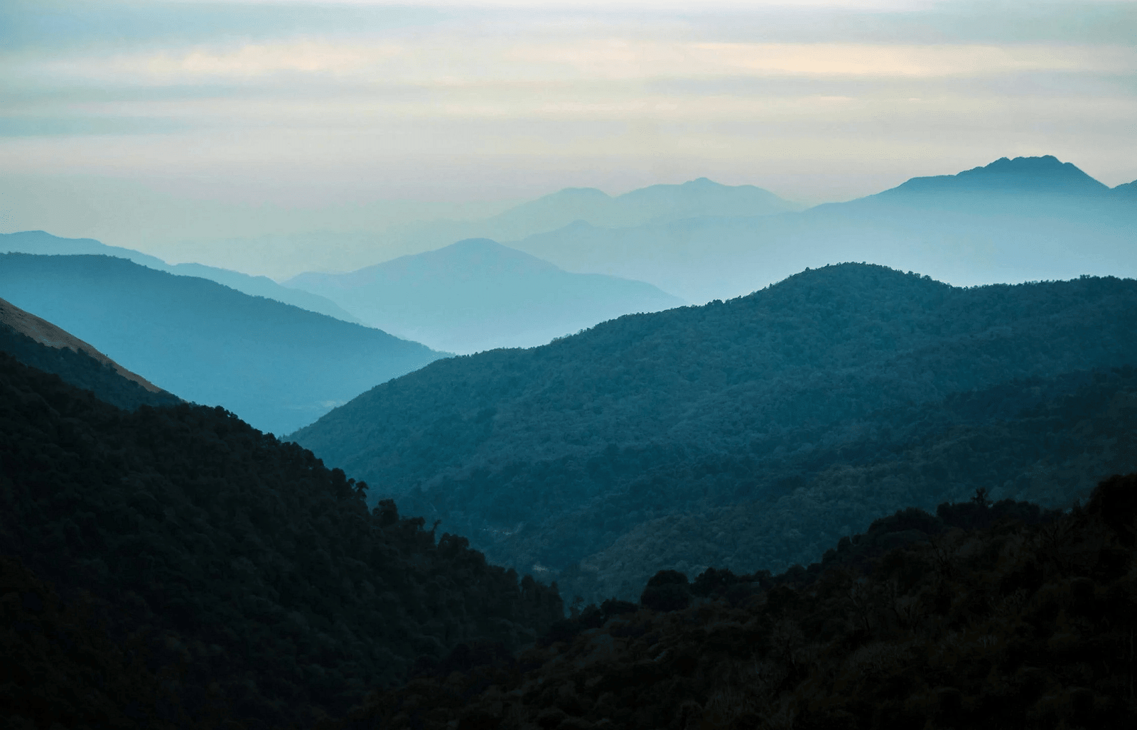 Serene landscape of misty mountains shrouded in a veil of clouds.