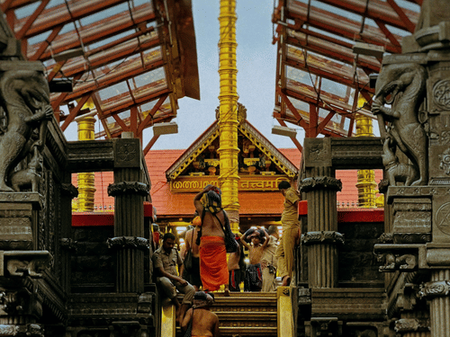 People gathered inside a temple hall looking toward a shrine with pillars and a wooden roof above.