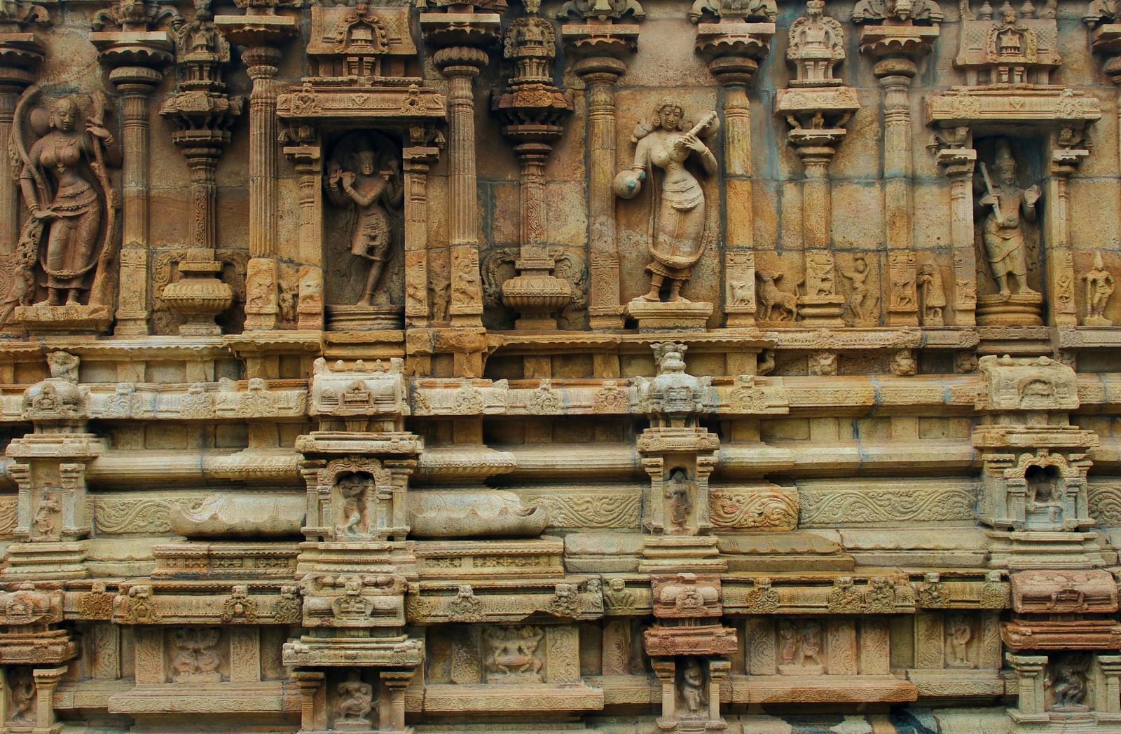 A detailed, close-up view of the intricate carvings and sculptures on the exterior wall of an ancient stone temple.