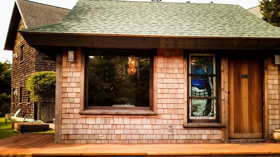Exterior view of a rustic cabin with wooden siding, green roof, and large windows - Brewery Gulch Inn & Spa