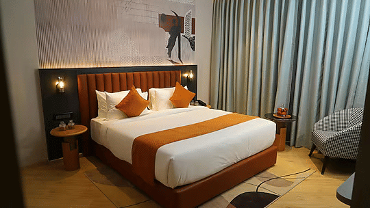 Modern hotel room with king size bed, pillows, and seating area at Ramada Encore by Wyndham Chandigarh Zirakpur.