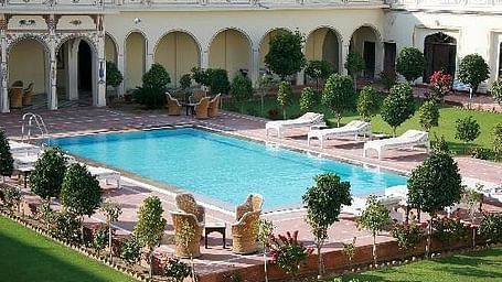 A facade of Indra Vilas with a swimming pool at the centre