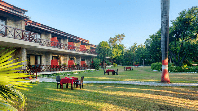 Resort building with a balcony overlooking green lawns and trees.