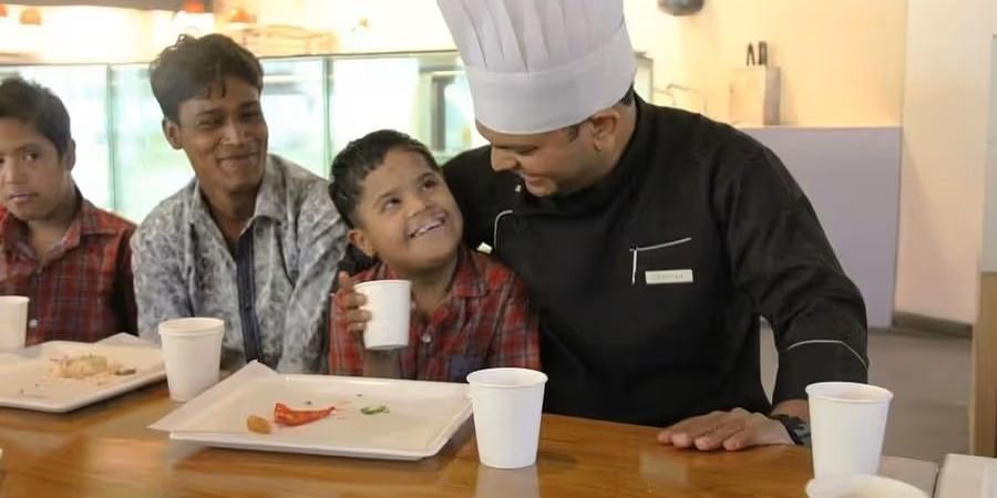 Chef engaging with children during a culinary workshop orgnaised by Clarks Amer