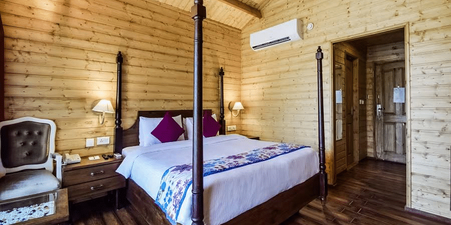 A cosy room with wooden walls, a four-poster bed, and a vintage chair. - Bamboo Saa Resort & Spa, Udaipur