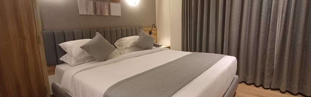 Family Suite at Hotel Paai, Hosur featuring a double size bed, a wardrobe, and a window with curtains drawn.