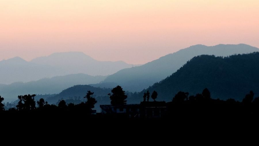 Soft, pastel hues paint the sky as the sun sets over the layered mountain ranges, creating a serene and picturesque landscape, possibly a tranquil evening view from the resort