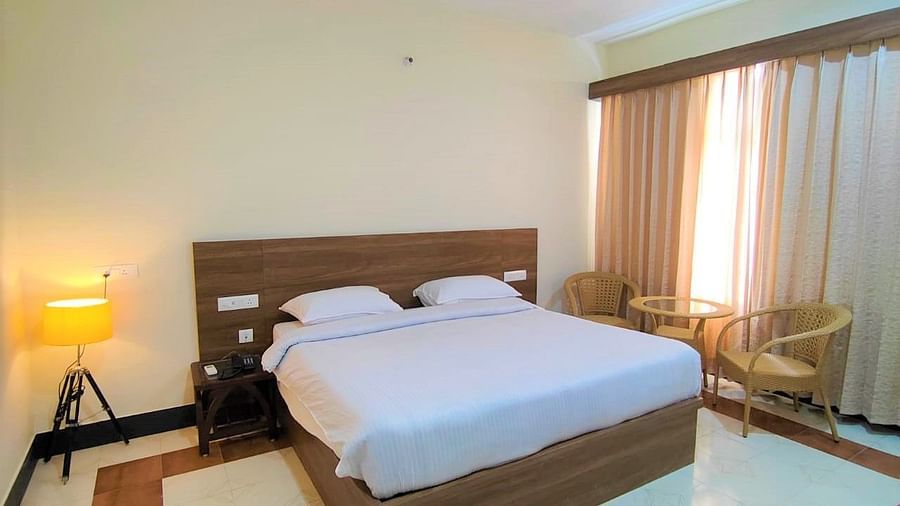 Room at Pride Resort Rudraprayag featuring a double bed with a wooden headboard with a floor lamp in the corner and a sitting space right next to the window