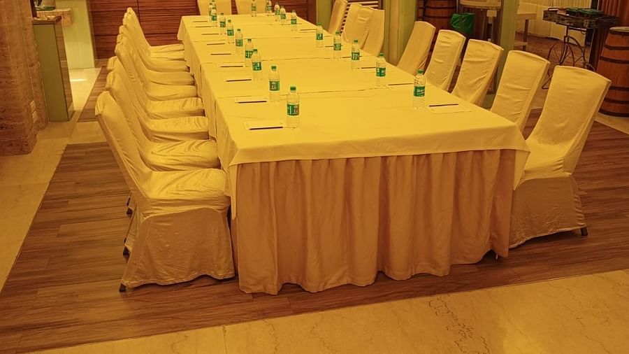 Narrow conference room setup with golden chair covers and a long rectangular table at Mirage Hotel, Mumbai.