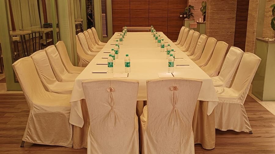 Boardroom-style table setup with white draped chairs and a warm ambience, suited for business meetings at Mirage Hotel, Mumbai.