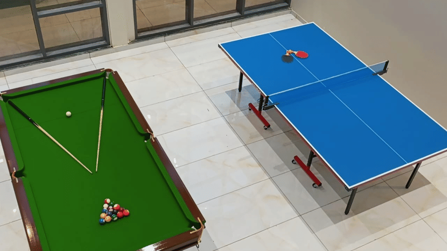 The dedicated games room at Vinti Resort, Ambaji, offers a full-sized pool table set up with cues, and a blue table tennis table.