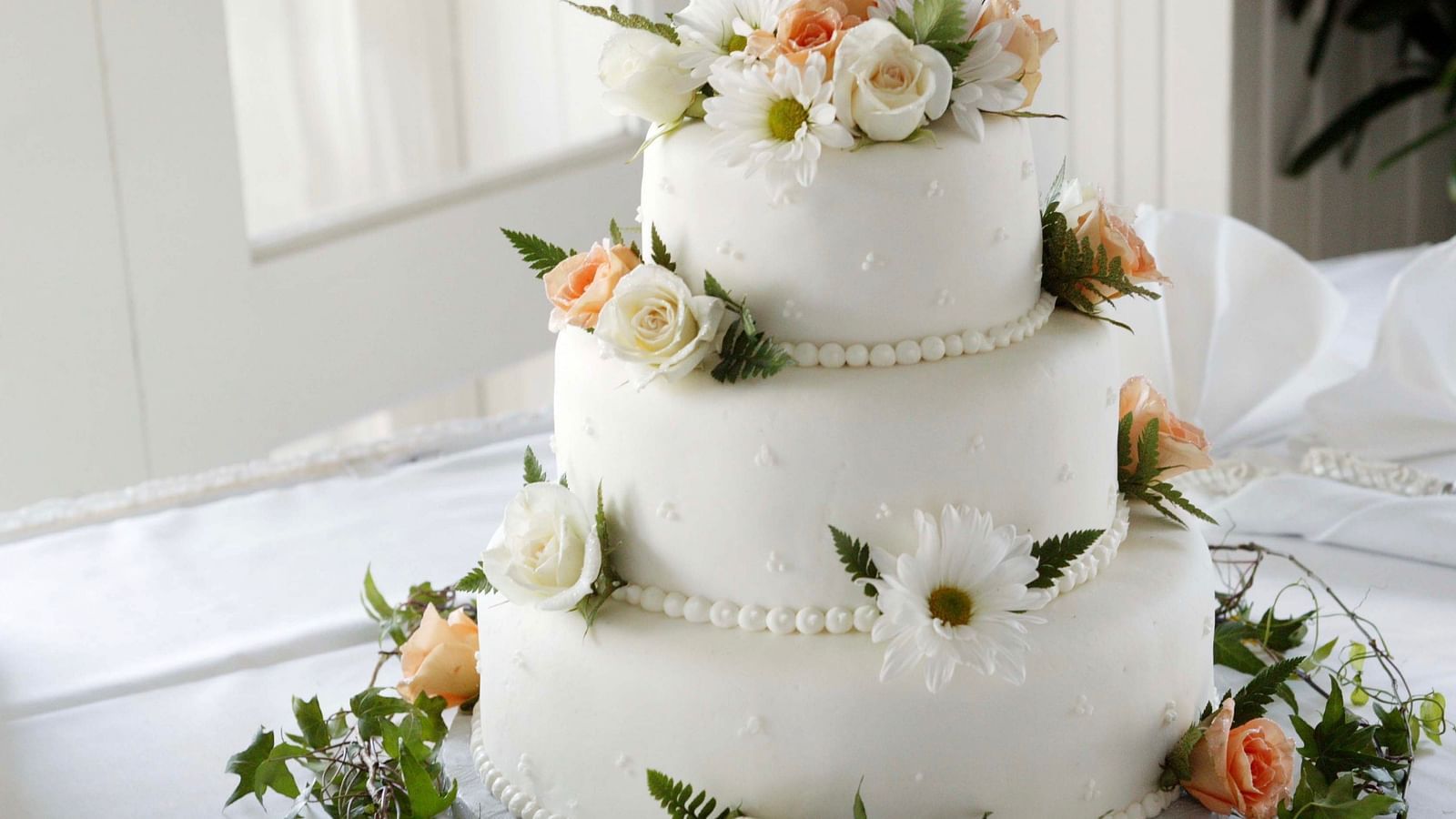 a three tier wedding cake with flowers and other things kept on it for decoration