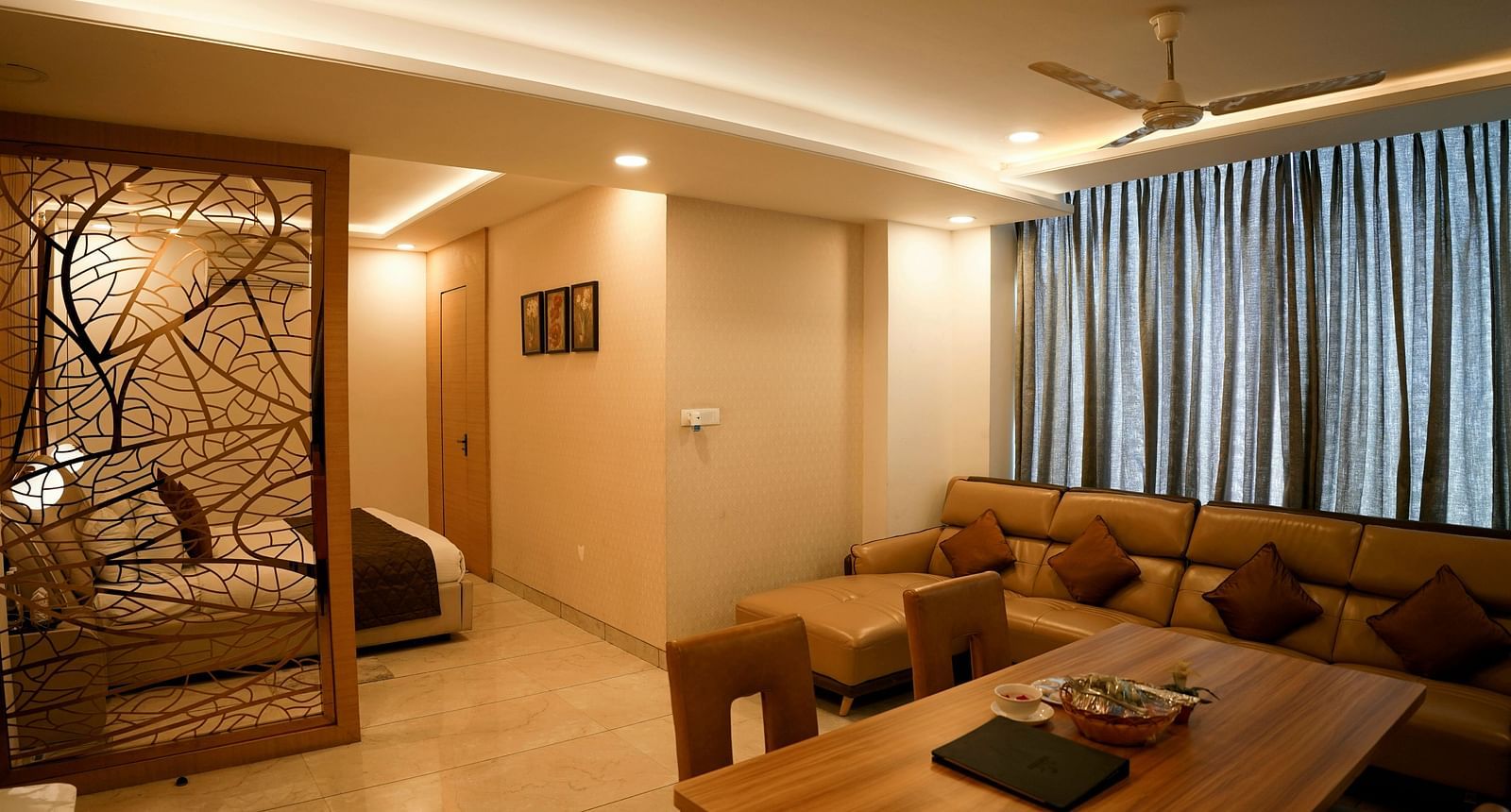 A spacious living room with a sectional sofa and decorative partition leading to another room - TGI Insignia, Bhopal