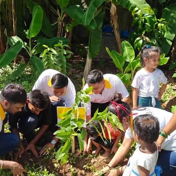 Bawa Group of Hotels Children and adults planting trees in a green, outdoor environment for environmental care.