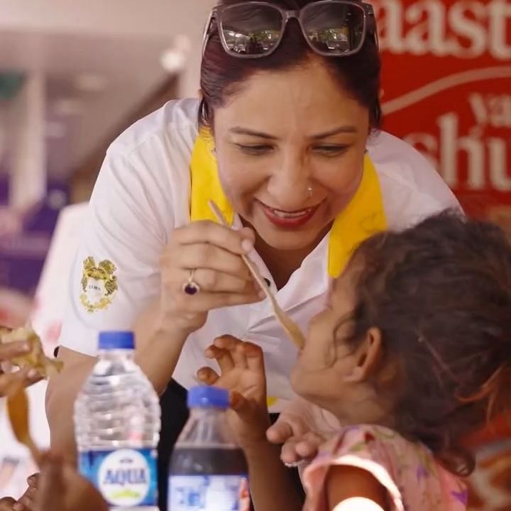 Bawa Group of Hotels A woman feeding a child, both smiling, with bottles of water and food around them