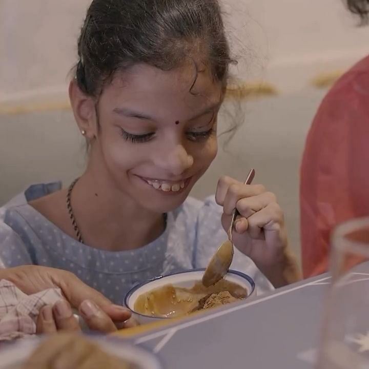 Bawa Group of Hotels A young girl enjoying a meal, sitting at a table with a laptop and food items.