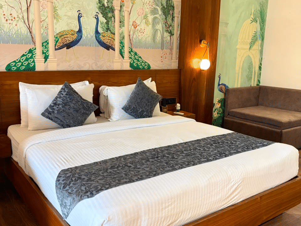 Emperor Room, King bed beneath the hand-painted peacock mural