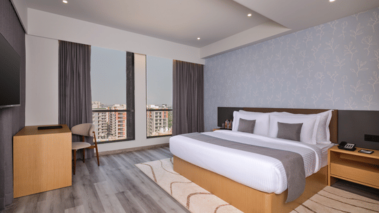 Double bedroom with large windows and minimalist decor - Pride Elite Gandhinagar
