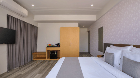 Modern hotel room with king bed and wooden wardrobe - Pride Elite Gandhinagar
