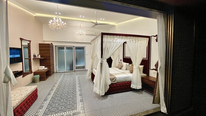A plush bed and the room of Moghul from the lawn outside at nighttime at Zara's Resort