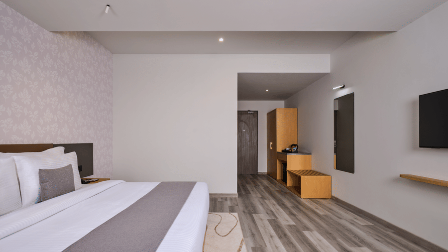 Minimalist master bedroom with hardwood flooring and vanity area - Pride Elite Gandhinagar