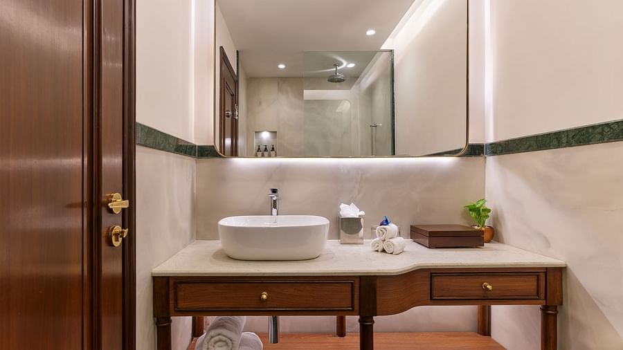 The Premium King Garden View Room at The Ummed Ahmedabad features an elegant ensuite bathroom with a well-lit sink, mirror, and spacious counter