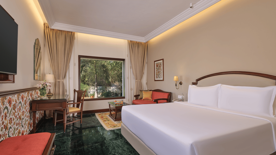 The Premium King Garden View Room at The Ummed Ahmedabad featuring a spacious interior with warm lighting and a king size bed facing the TV mounted on the wall