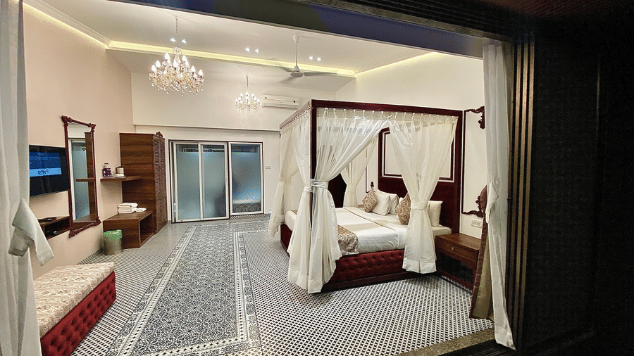 A plush bed and the room of Moghul from the lawn outside at nighttime at Zara's Resort