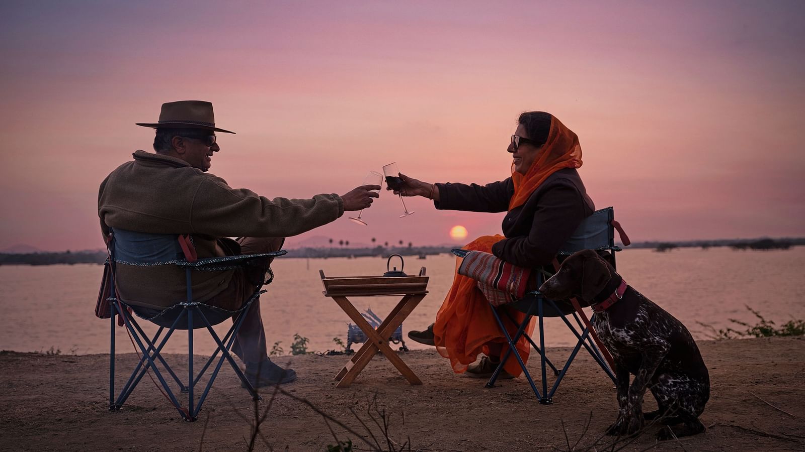 image of a couple enjoying the sunset as they cling wine glasses at Dev Shree, Deogarh