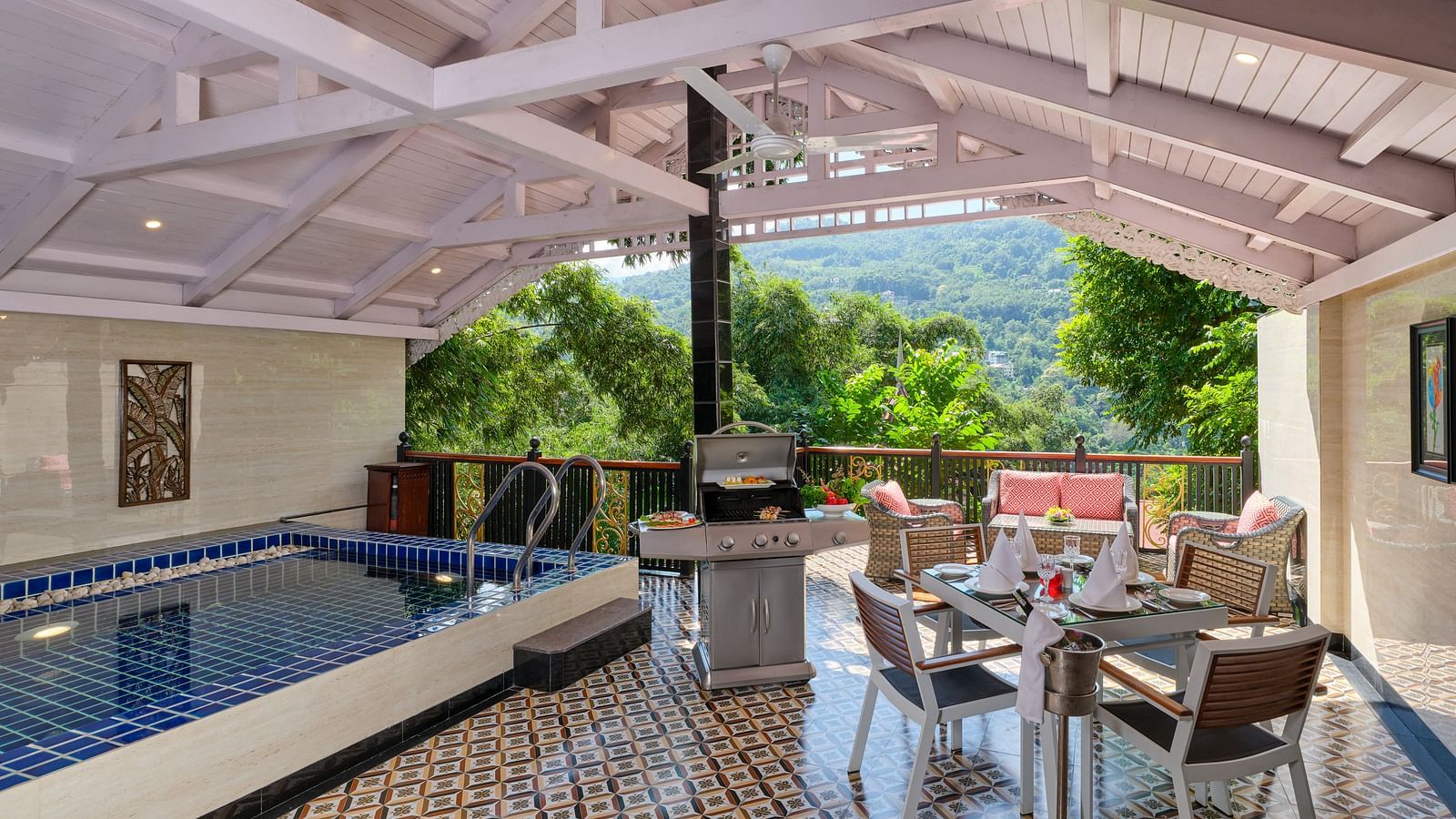 Swimming pool in Imperial Villa with a sating area and barbecue grill with a wooden ceiling and a balcony overlooking greenery.